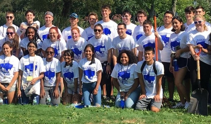 Leadership House students pose in white shirts with a blue buffalo on them in front of the gardens at the Erie County Botanical Garden. 